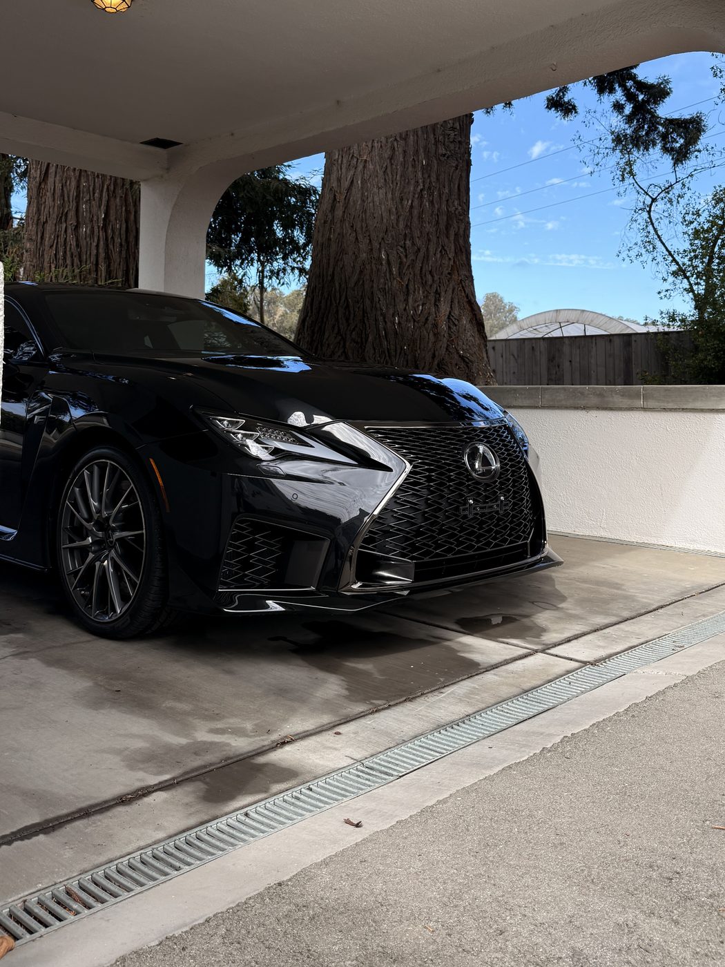 A black Lexus RC F under a carport after a wash